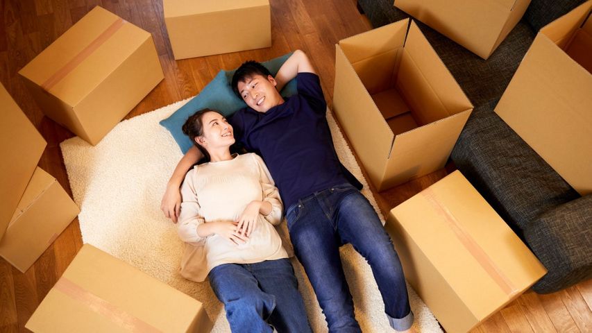 couple laying on floor with moving boxes around them