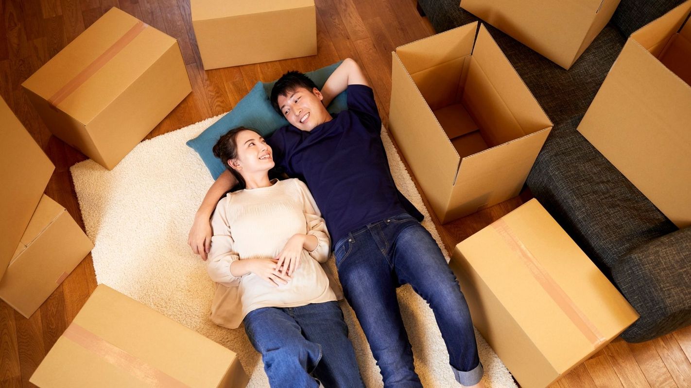 couple laying on floor with moving boxes around them