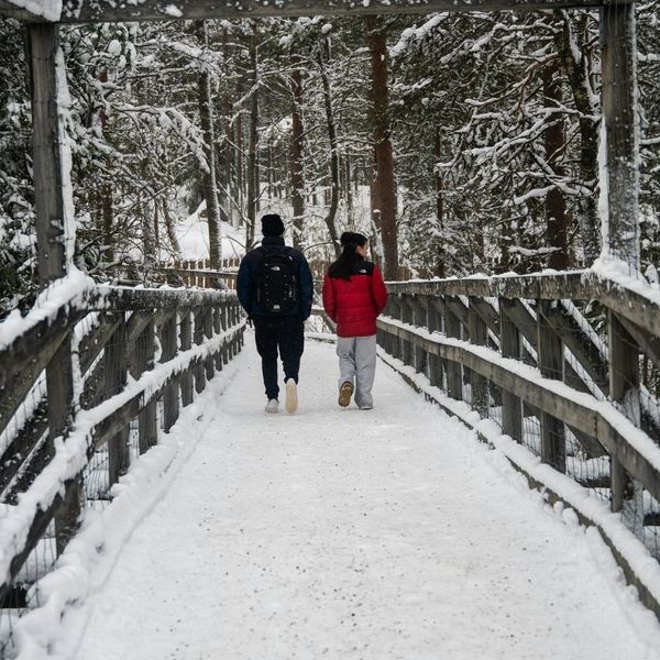 two people walking across a snowy pedestrian bridge