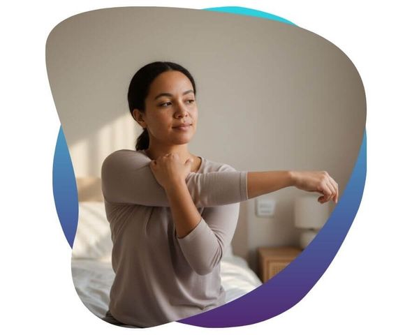 Woman performing a guided shoulder stretch in a bedroom.