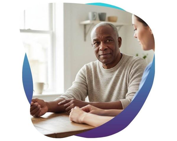 Senior man speaking with a healthcare professional at home.