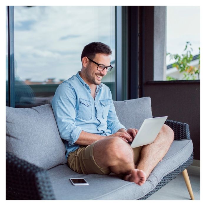 smiling man working remotely from a couch