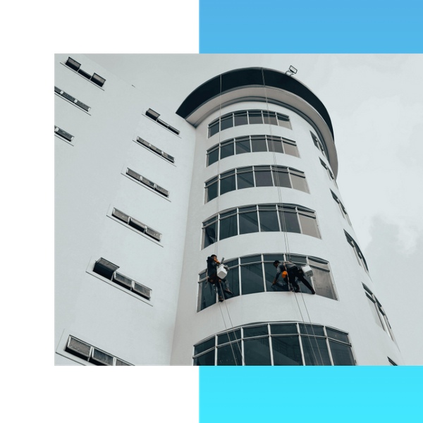 Two people are cleaning windows on a large building