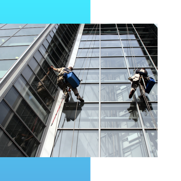 Two people cleaning windows on commercial buildings