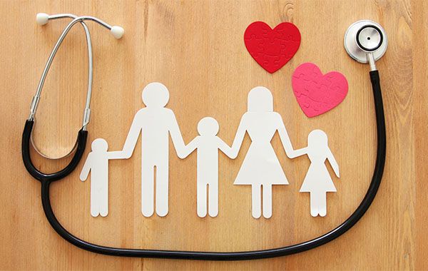 paper cut out of family with stethoscope and hearts on a desk