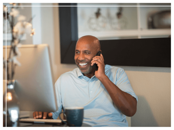 Smiling man talking on phone while using computer