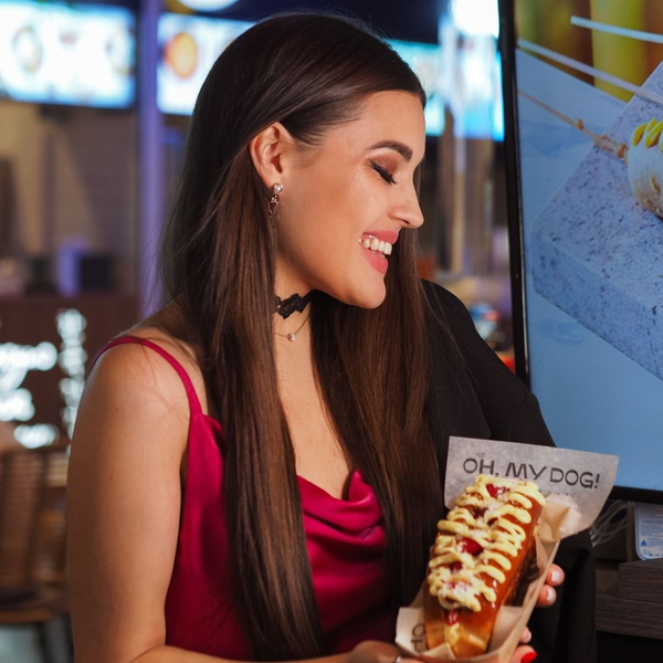 woman in pink dress holds hot dog and smiles Make Your Next Event Memorable with Detroit's Finest Hot Dog Trucks 1.jpg