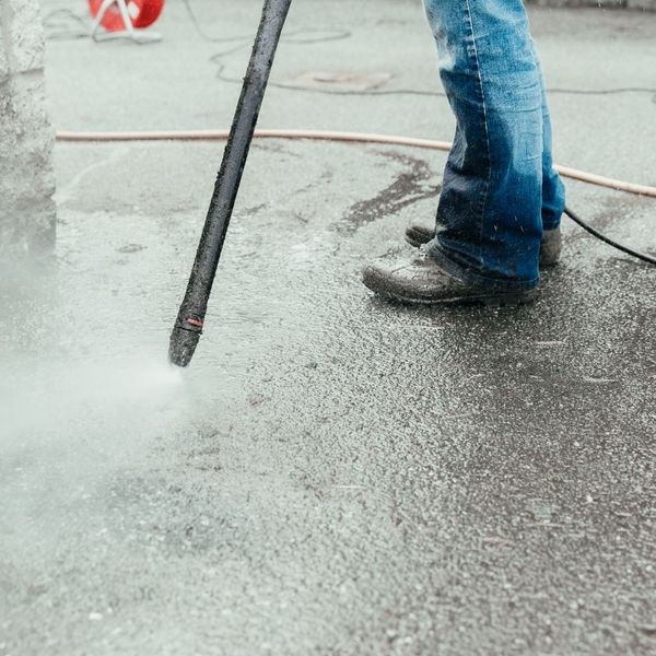 Person power washing an asphalt driveway.