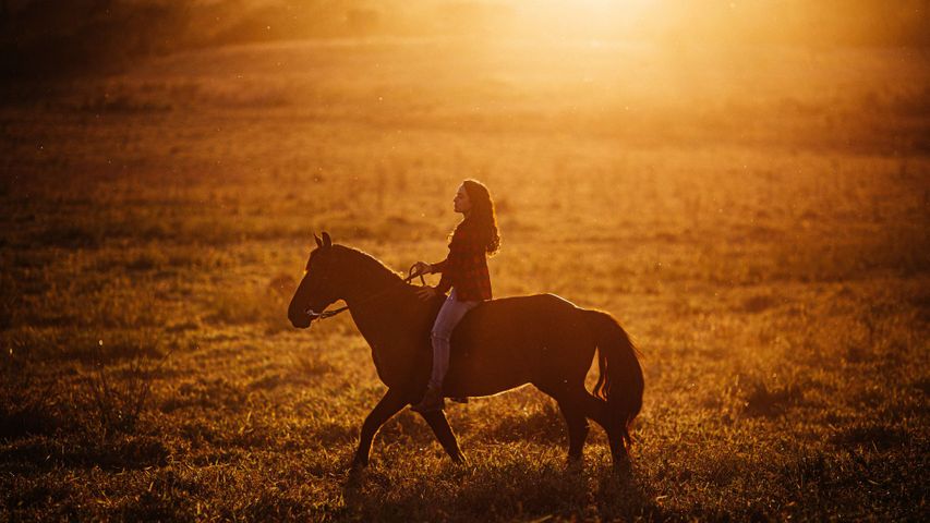 woman riding horse at sunset