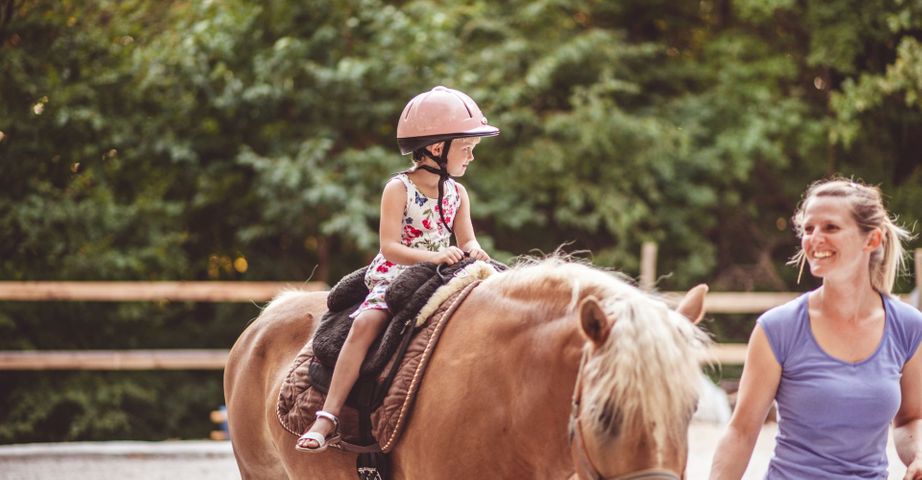 A little girl taking a horseback riding lesson