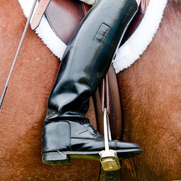 close up of a person wearing riding boots while riding on a horse