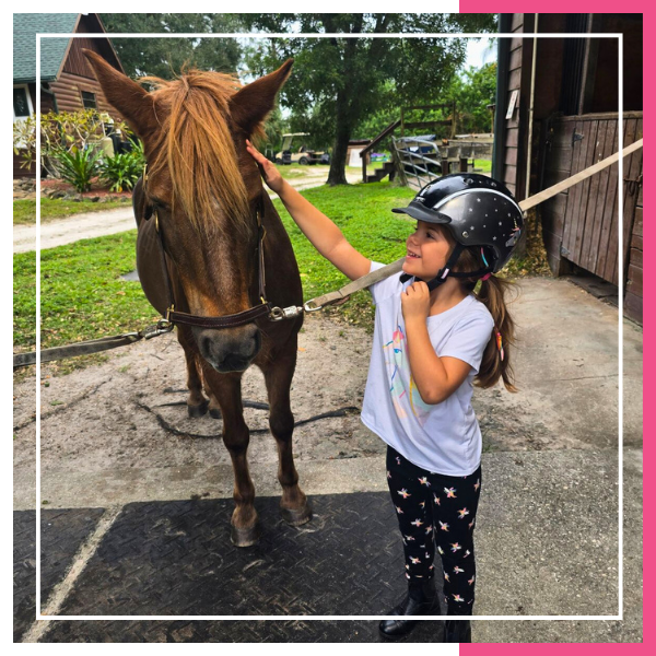 girl smiling patting horse