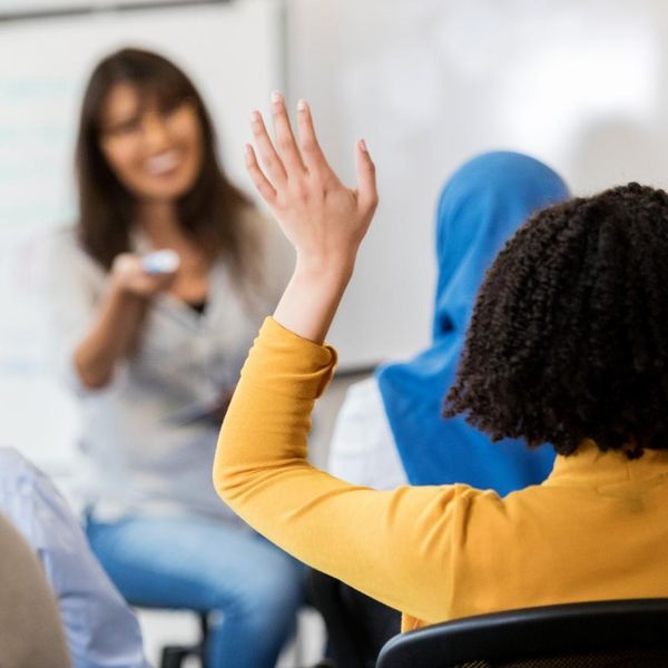 adult woman raising her hand in class