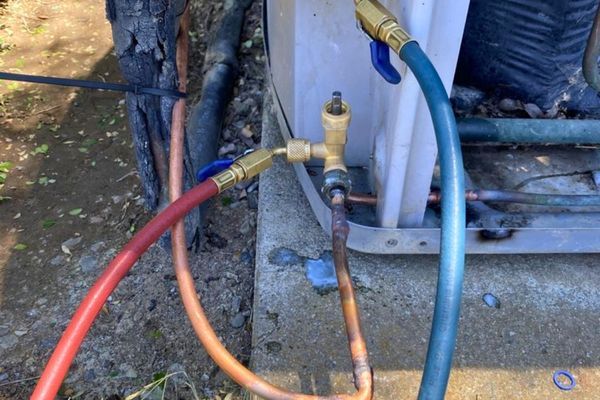 a section of the outdoor HVAC condenser unit where a technician is performing a procedure
