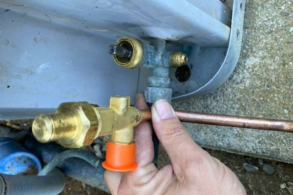 a technician holding a a Thermal Expansion Valve (TXV)