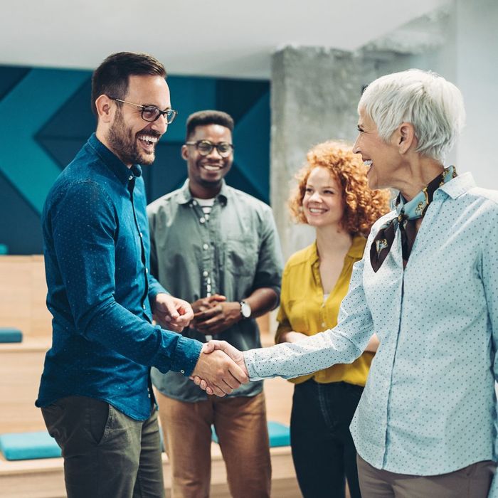 Four people talking and shaking hands