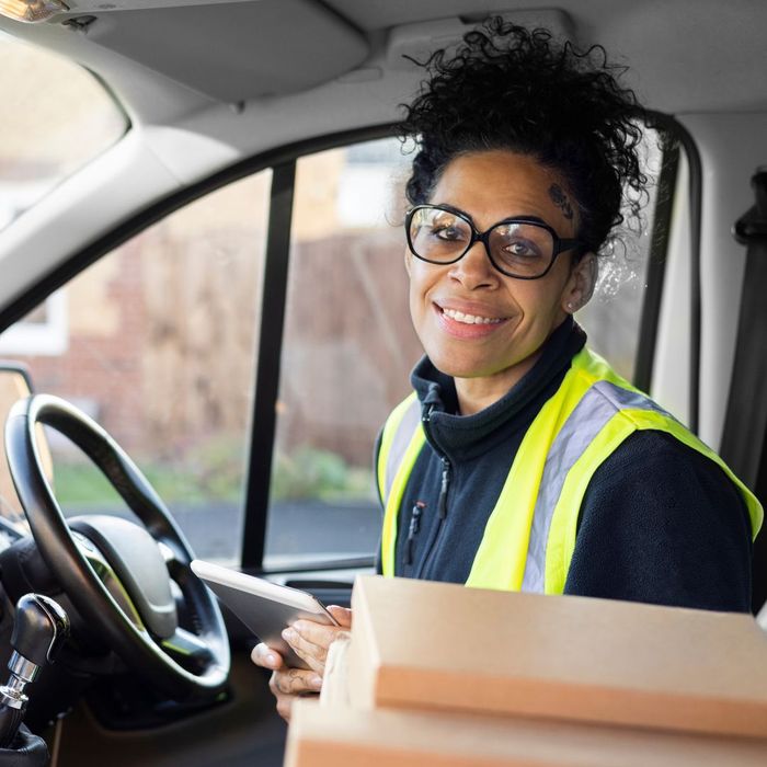 A cargo van driver smiling in her van