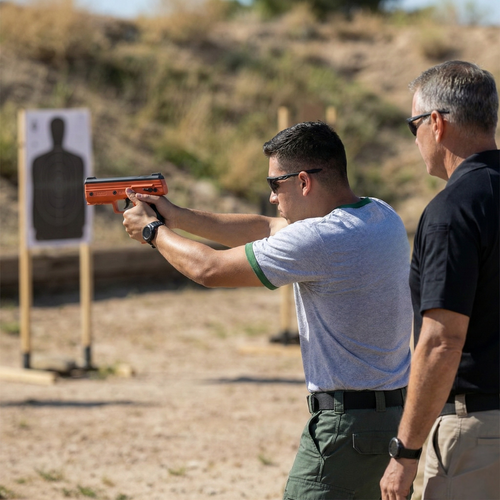 A student at the ADF Training Facility practices firing an orange Byrna training launcher at a silhouette target during a certification course.