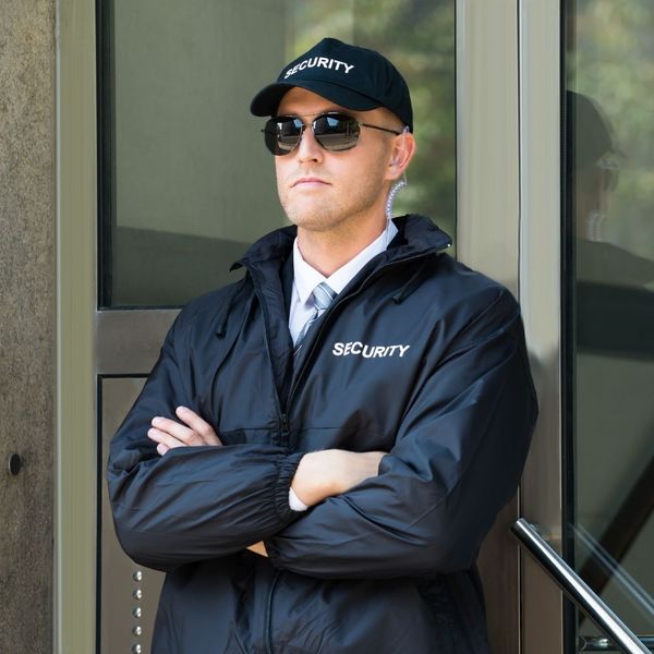 security guard at work wearing sunglasses, arms folded