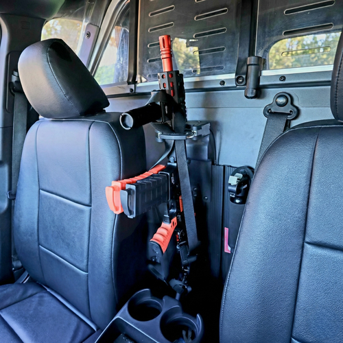 Close-up of a Byrna less lethal projectile launcher securely mounted in a professional level-retention rack between the front seats of a patrol vehicle.