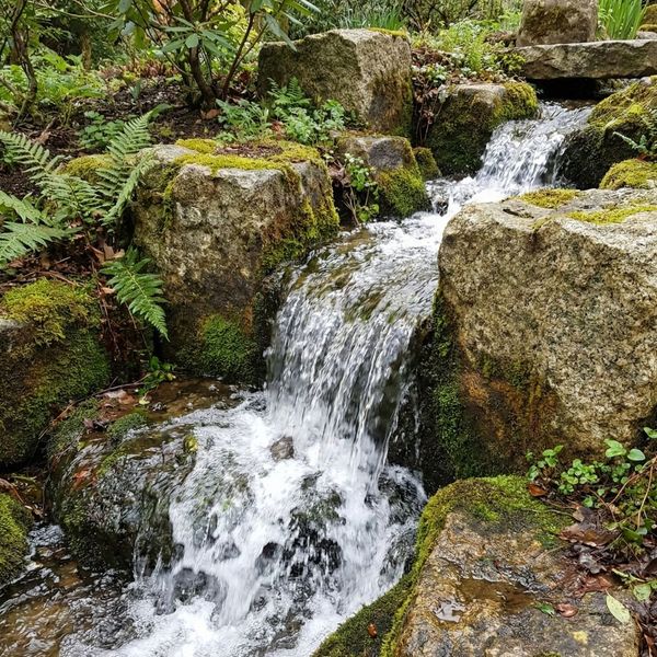A close-up of a natural stone waterfall with water cascading over rocks, emphasizing movement and sound.