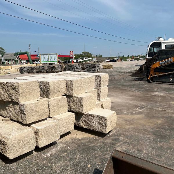Ozark Stone Yard supply lot featuring a skid steer and diverse pallets of stone, offering a wide variety of landscape rock for Midwest customers.