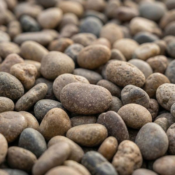 Close-up of a landscape bed filled with smooth, round river rock, a popular decorative and functional landscape rock for drainage.