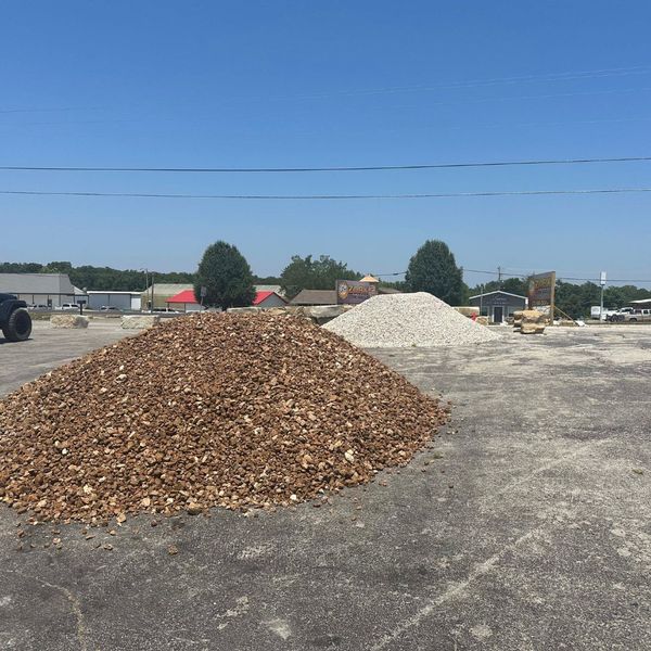A large bulk pile of brown crushed wholesale rock at Ozark Stone Yard, suitable for various drainage applications.