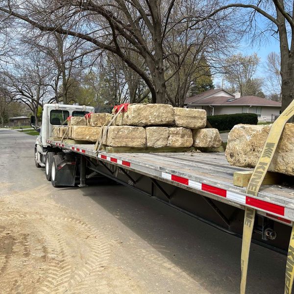 Flatbed semi-truck loaded with heavy limestone blocks, demonstrating our reliable wholesale rock delivery service for large projects in Missouri.