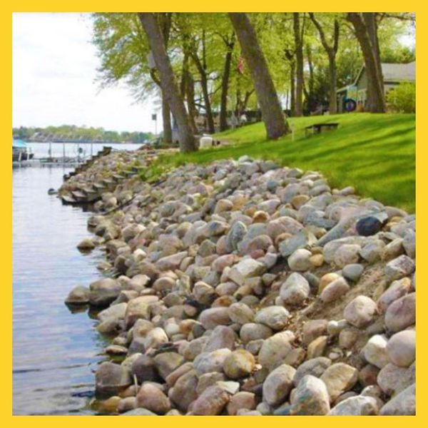 river rocks between body of water and grass berm