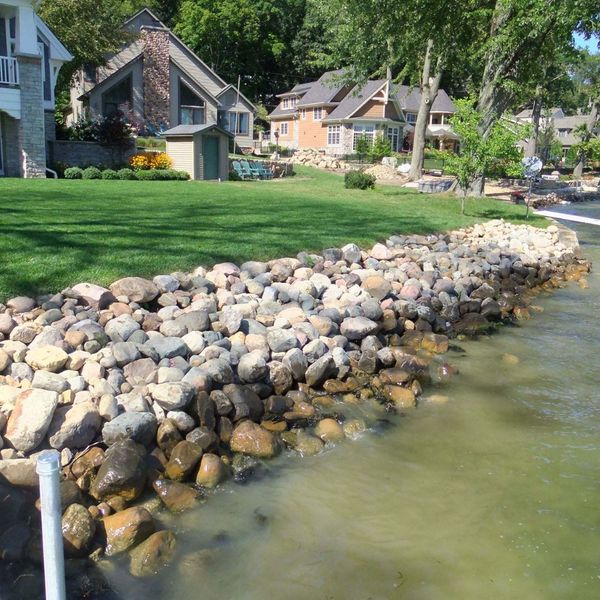 Large shoreline erosion control project using heavy rip rap landscape rock to stabilize the bank against water flow.