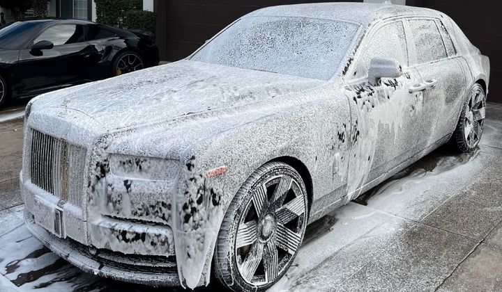 White luxury vehicle covered in suds during a premium exterior detailing service.