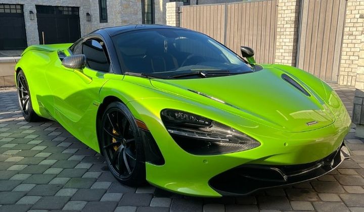 Bright lime green sports car with a high-gloss finish parked on a paved driveway.