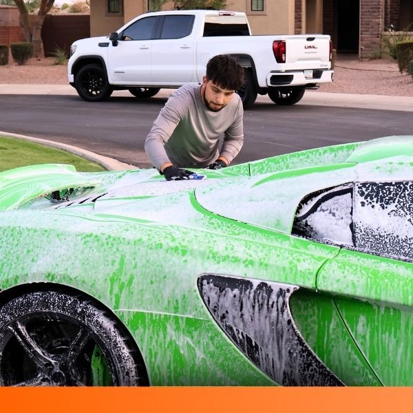 A detailer wiping down the exterior of a bright green sports car.