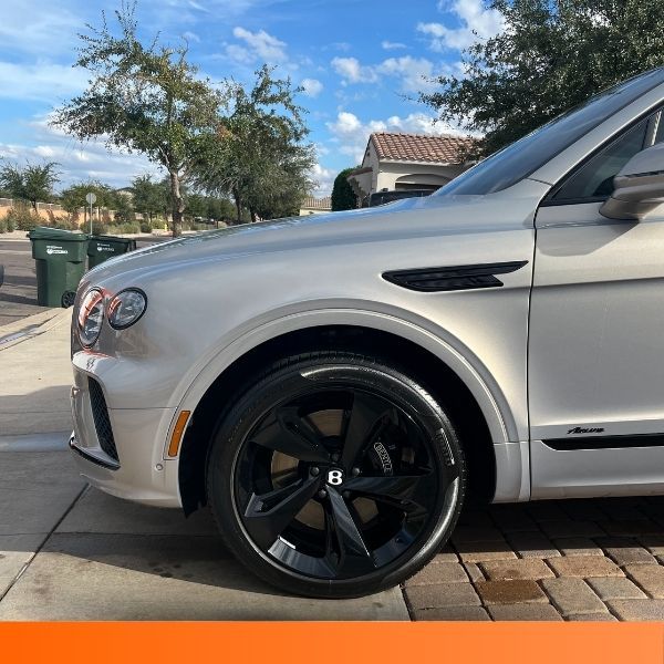 Side profile of a silver Bentley Azure SUV parked on a brick driveway.