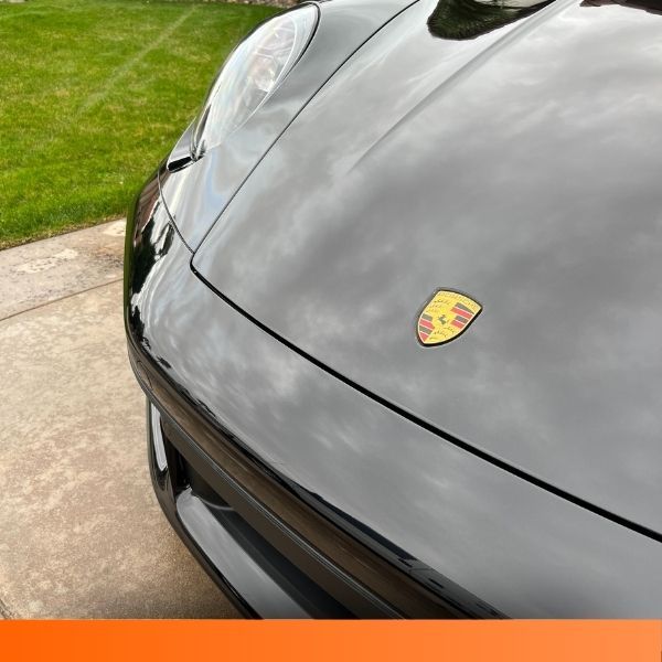 Close-up of a highly polished black Porsche hood showing deep reflections.