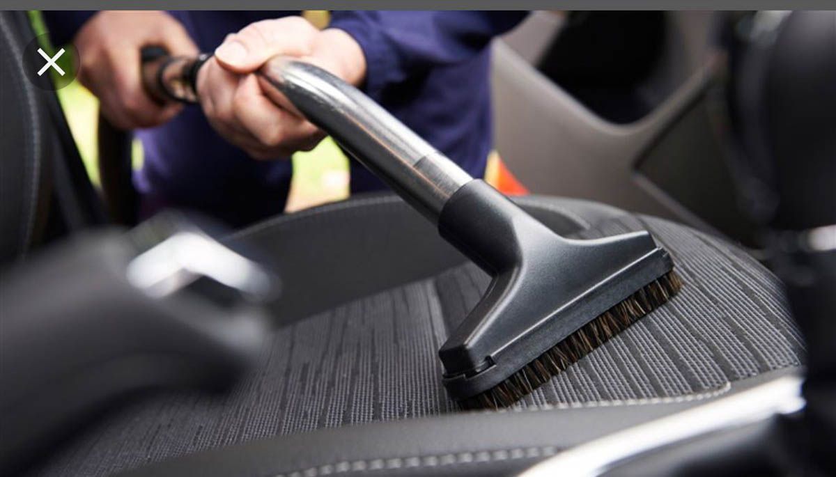 Premium AI Image  Joyful auto detailer vacuum cleaning open car boot Car  detailing and car care concept