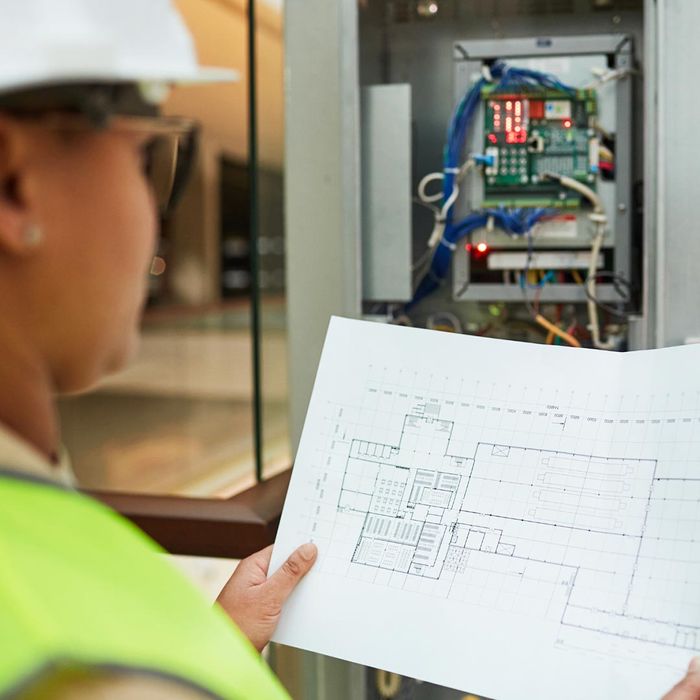 electrician next to an electrical box looking at electrical plans