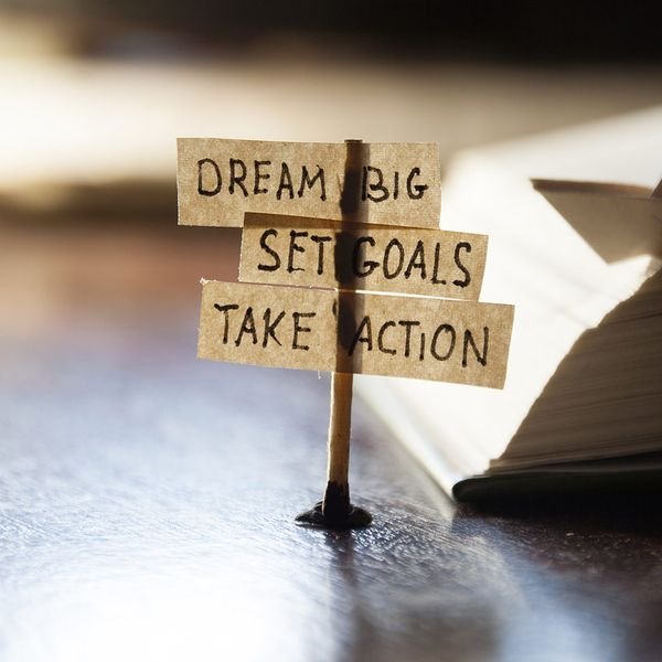 image of a stick with notes on a desk that say “dream big, set goals, take action.”