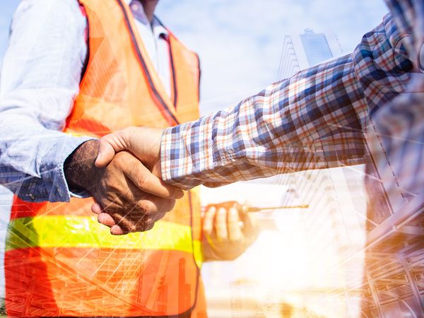 Architect contractor shaking hands with a client at a construction site