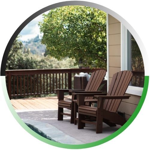 Circular icon of a peaceful backyard patio with two wooden Adirondack chairs facing a scenic valley view.