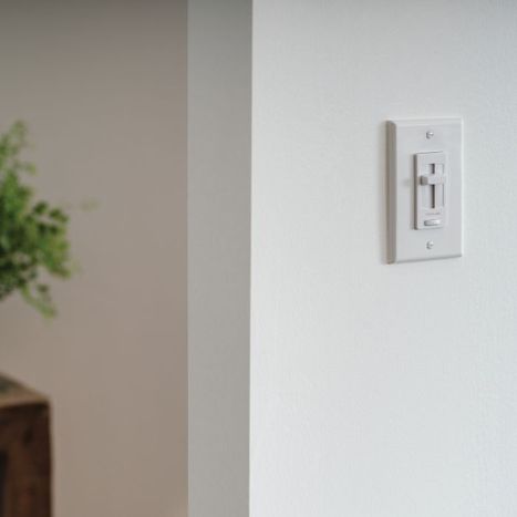 Close-up view of a modern white light switch plate on a white wall.
