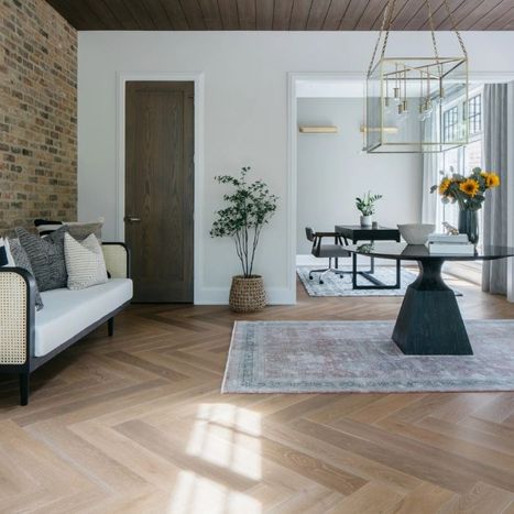 Modern living room featuring a sofa, round table, and luxury vinyl plank flooring laid in a herringbone pattern.