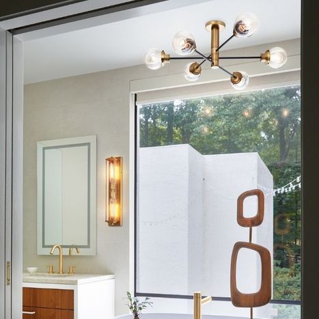 Modern bathroom interior featuring a brass sputnik-style chandelier and a rectangular vanity mirror.