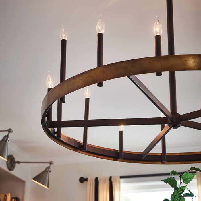 A close-up of a large, rustic wagon-wheel chandelier with candle-style bulbs hanging from a white ceiling. A close-up of a large, rustic wagon-wheel chandelier with candle-style bulbs hanging from a white ceiling.
