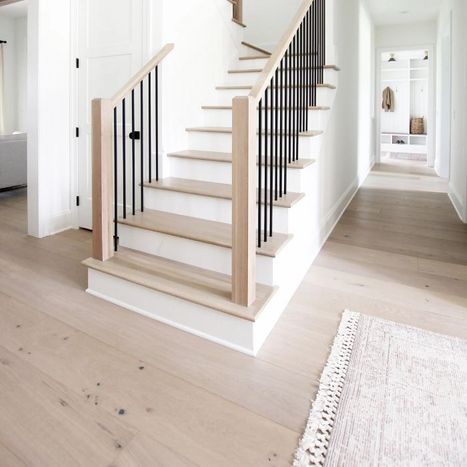 Light wood staircase with white risers and a black metal stair railing.