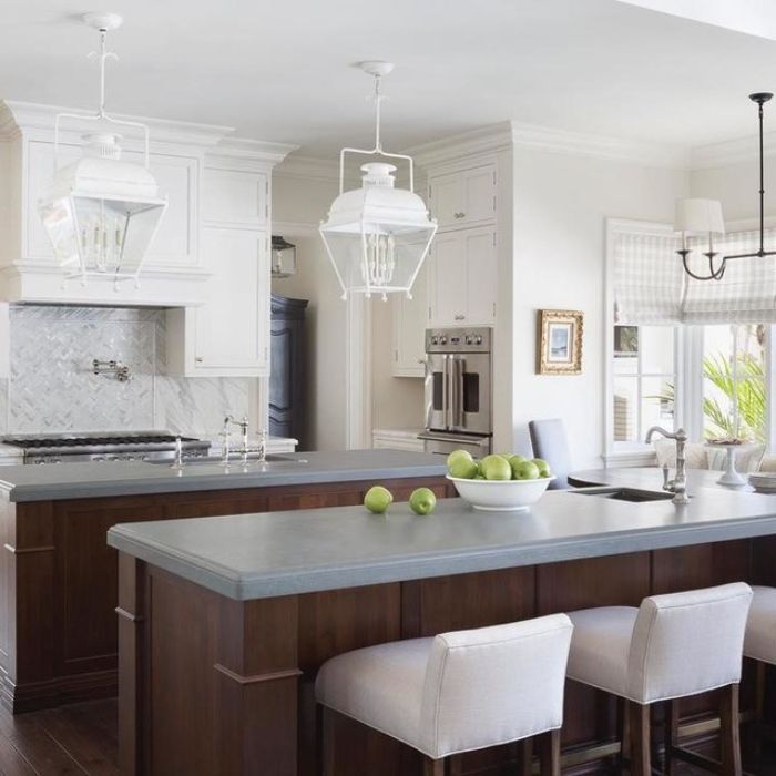 Two white pendant lights hang over a dark wood kitchen island. The pendants are lantern-style with clean lines and a metal frame. The kitchen features white upper cabinets, a light gray countertop, and a white subway tile backsplash. Two white pendant lights hang over a dark wood kitchen island. The pendants are lantern-style with clean lines and a metal frame. The kitchen features white upper cabinets, a light gray countertop, and a white subway tile backsplash.