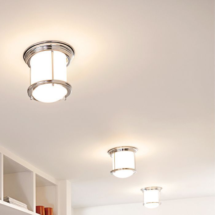 Three modern, cylindrical flush-mount lights with chrome details are installed in a row down a hallway with a white ceiling.