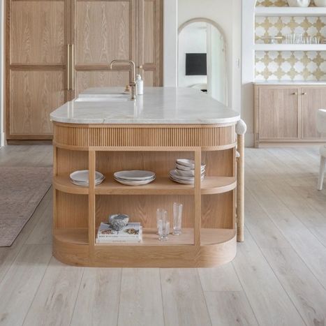 Light wood kitchen island with open rounded shelving sitting on luxury vinyl plank floors.