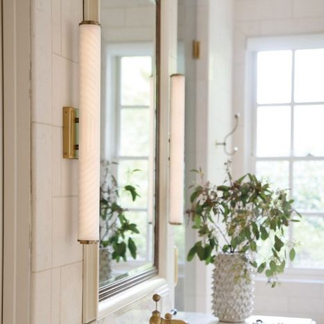 Bathroom vanity area featuring tall mirrors and modern brass tube sconces.